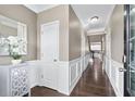 Inviting hallway with hardwood floors, white wainscoting, and modern lighting fixtures at 2939 Woodward Down Trl, Buford, GA 30519