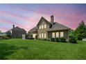 Backyard view at dusk featuring expansive green lawn, garden shrubbery, and shaded patio area at 390 Scott Farm Dr, Powder Springs, GA 30127