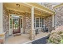 Charming brick home featuring a covered front porch and decorative glass front door at 390 Scott Farm Dr, Powder Springs, GA 30127