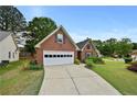 Quaint brick home with an attached garage and driveway, surrounded by lush green lawns at 4730 Fairway View Ct, Duluth, GA 30096