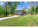 Spacious backyard with a new driveway, a wooden fence, and a home with well-maintained lawn surrounded by trees at 256 Grist Mill Ln, Lawrenceville, GA 30046