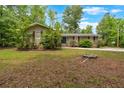 Charming one-story home with a well-manicured lawn and mature trees and a green front door at 7370 N Mitchell Ct, Villa Rica, GA 30180