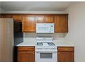 Kitchen featuring wooden cabinets, white appliances, and neutral countertops, offering a clean and functional space at 107 Providence Run, Dallas, GA 30157