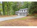 View of home with attached 2 car garage and long concrete driveway surrounded by trees at 798 Brownlee Ln, Lawrenceville, GA 30044