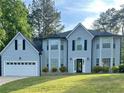 Charming two-story home with gray siding, attached garage, and manicured lawn at 6940 Treeline Dr, Cumming, GA 30028