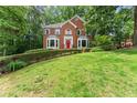 Traditional brick home with manicured lawn and garden beds under mature trees at 1172 Malvern Hunt Ct, Lawrenceville, GA 30043