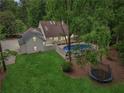 Aerial view of a backyard with a swimming pool, trampoline, and lush green lawn surrounded by mature trees at 400 N Peachtree Pkwy, Peachtree City, GA 30269
