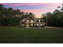 Charming two-story home with stone and shake siding, lush lawn, and mature trees at sunset at 100 Chantilly Ln, Fayetteville, GA 30215