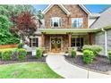 Inviting front porch with wooden columns, stone accents, and lush landscaping creates a warm welcome at 100 Chantilly Ln, Fayetteville, GA 30215