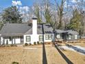 Attractive home featuring a gray roof, white and gray paint, a chimney, and a manicured lawn at 1571 Boulevard Lorraine Sw, Atlanta, GA 30311