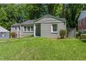Gray brick and siding house with a well-maintained lawn and view of the surrounding greenery at 2025 Venetian Sw Dr, Atlanta, GA 30311