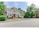 Beautiful two-story home with a welcoming red door, landscaped yard, balcony, and attached two-car garage at 7520 Ledgewood Way, Suwanee, GA 30024