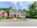 Elegant two-story home with a red front door, balcony, landscaped yard, and convenient two-car garage at 7520 Ledgewood Way, Suwanee, GA 30024