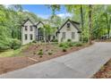 Charming painted brick home with an extended driveway surrounded by lush landscaping and mature trees at 2680 Spalding Dr, Atlanta, GA 30350