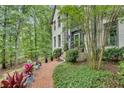 Home featuring a painted brick front entrance with manicured bushes, trees, and a brick walkway at 2680 Spalding Dr, Atlanta, GA 30350