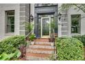 Home's front entrance features a gray painted door, brick stairs, decorative plants, and modern sconces at 2680 Spalding Dr, Atlanta, GA 30350