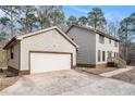 View of the home's exterior, featuring a detached garage with a large white door and light colored siding at 1791 Lake George Dr, Lithia Springs, GA 30122