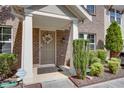 Close-up of townhome entrance showcasing a charming wreath, brick facade, and well-maintained landscaping at 1570 Shire Village Dr, Sugar Hill, GA 30518
