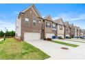 A row of brick townhomes featuring well-maintained lawns and concrete driveways at 2170 Trelipe Dr, Lawrenceville, GA 30044