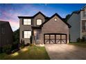 Evening view of a two-story brick home featuring a two-car garage, and landscaped front yard at 456 Crestmont Ln, Canton, GA 30114
