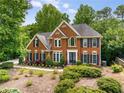 Two-story brick home with blue shutters surrounded by lush landscaping, creating a private and inviting ambiance at 710 Devon Hill Ct, Roswell, GA 30075
