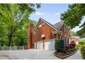 Brick home featuring a two-car garage, spacious driveway, and well-maintained landscaping at 710 Devon Hill Ct, Roswell, GA 30075