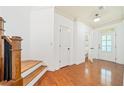 Bright foyer with hardwood floors, staircase with wood banister, and white trim at 8360 Village School Dr, Cumming, GA 30041