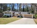 Well-maintained single-story home with a paved driveway, attached garage, and mature trees at 1978 Fisher Trl, Atlanta, GA 30345