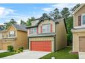 Two-story home features a red garage door, green trim, and is set on a well-manicured lawn at 6571 Splitpine Ct, Atlanta, GA 30349