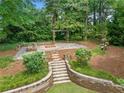 Stone staircase leading to an outdoor entertaining area with a firepit, pergola, and lush landscaping at 3019 Haverford Se Ln, Marietta, GA 30067