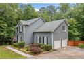 Two-story home featuring a two-car garage, gray siding, mature trees, and well-maintained landscaping at 49 Timberlake Ne Cv, Cartersville, GA 30121