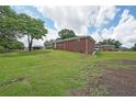 Expansive lawn surrounds brick home with a glimpse of multiple structures on the property at 629 Birchwood Rd, Marietta, GA 30060