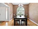 Formal dining room featuring textured walls, hardwood floors, a large window, and chandelier at 174 Saint Georges Ct, Suwanee, GA 30024