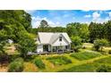 Inviting white farmhouse surrounded by trees, landscaping, and a lush garden at 10975 Hutcheson Ferry Rd, Chattahoochee Hills, GA 30268