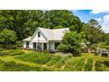 Lovely farmhouse showcasing a large yard and beautiful landscaping at 10975 Hutcheson Ferry Rd, Chattahoochee Hills, GA 30268