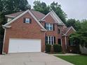 Beautiful two-story brick house featuring an attached garage, manicured shrubs and a long driveway at 1558 Ember Oaks Cir, Powder Springs, GA 30127