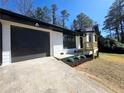 Close up of the exterior highlighting the home's new dark painted garage door, black trim, and wood porch at 2400 Glenrock Dr, Decatur, GA 30032