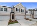 Beautiful townhome exterior featuring a two-car garage, with dark shuttered windows and a manicured lawn at 520 Amethyst Way, Stockbridge, GA 30281