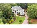 Aerial view of a stately home with a beautifully landscaped lawn, mature trees, and a winding driveway at 8957 Old Southwick Pass, Johns Creek, GA 30022