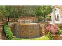 Elevated outdoor pool and spa featuring a stunning stone waterfall, surrounded by manicured landscaping at 8957 Old Southwick Pass, Johns Creek, GA 30022