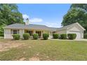Charming single-story home featuring a manicured lawn, mature landscaping, and an attached two-car garage at 100 Gum Creek Lndg, Oxford, GA 30054