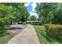 Long concrete driveway leads to a well-kept, single-story home surrounded by lush greenery and trees at 1095 Dallas Nebo Rd, Dallas, GA 30157