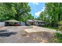 Single-story house with a driveway leading to a carport, surrounded by lush trees and a well-maintained lawn at 1095 Dallas Nebo Rd, Dallas, GA 30157