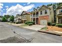 A suburban street showcasing homes with garages, driveways, and manicured lawns on a sunny day at 334 Pin Oak Ave, Woodstock, GA 30188