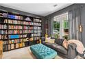 Cozy living room featuring custom built-in bookshelves, a comfortable sofa, and a large window with natural light at 4092 Grand Park Dr, Suwanee, GA 30024