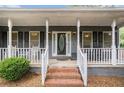 Inviting front porch with brick steps and classic white railings and cozy rocking chairs at 325 N Oakland Cir, Mcdonough, GA 30253
