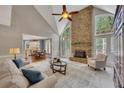 Bright living room with stone fireplace, ceiling fan, and large windows overlooking a lush yard at 3004 High Vista Walk, Woodstock, GA 30189