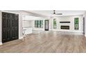 Bright, open-concept living area with wood floors, a modern fireplace, and black framed windows offering scenic views at 7619 Campground Rd, Cumming, GA 30040