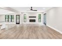 Spacious living area featuring wood-look floors, a modern fireplace, and views into the open-concept kitchen at 7619 Campground Rd, Cumming, GA 30040