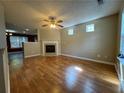 Bright living room with hardwood floors, a ceiling fan, and a cozy fireplace at 218 Osmanthus Way, Canton, GA 30114